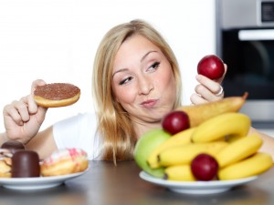 Pretty woman dithers between fruits or sweets